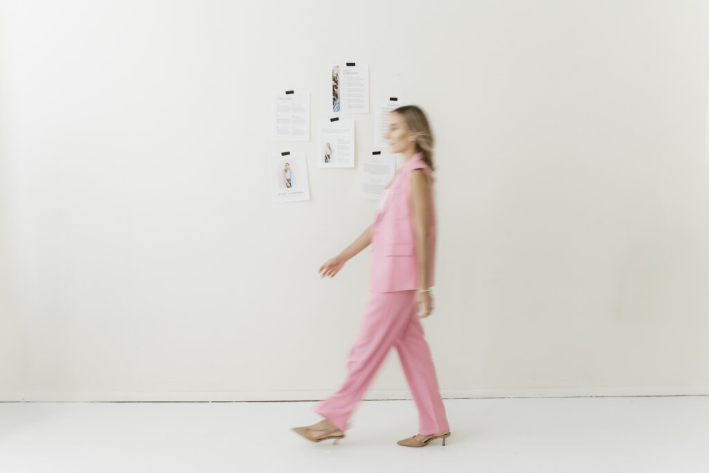 Business coach and creative mentor Kait walking past a vision board during an editorial studio branding session.